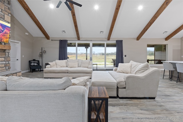 living room featuring ceiling fan, vaulted ceiling with beams, light wood-type flooring, and a healthy amount of sunlight