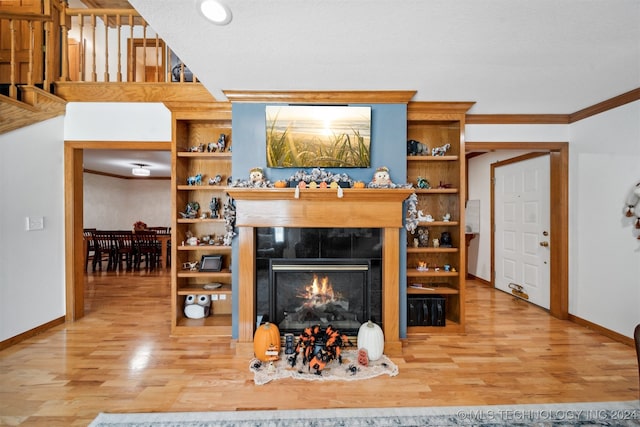 living room with light hardwood / wood-style flooring, a tiled fireplace, and crown molding