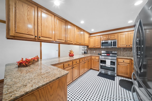 kitchen with kitchen peninsula, appliances with stainless steel finishes, light stone countertops, crown molding, and decorative backsplash