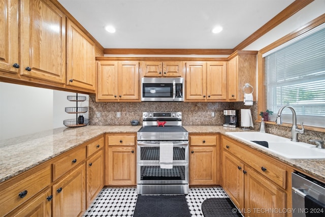 kitchen featuring light stone counters, sink, backsplash, appliances with stainless steel finishes, and crown molding