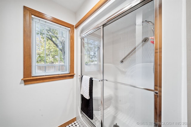 bathroom with a shower with door and tile patterned floors