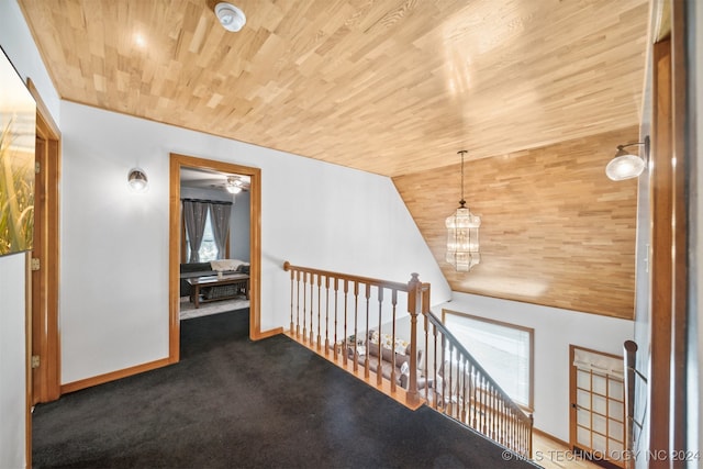 hallway with dark colored carpet, lofted ceiling, a chandelier, and wooden ceiling