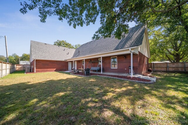 back of house with a patio and a lawn