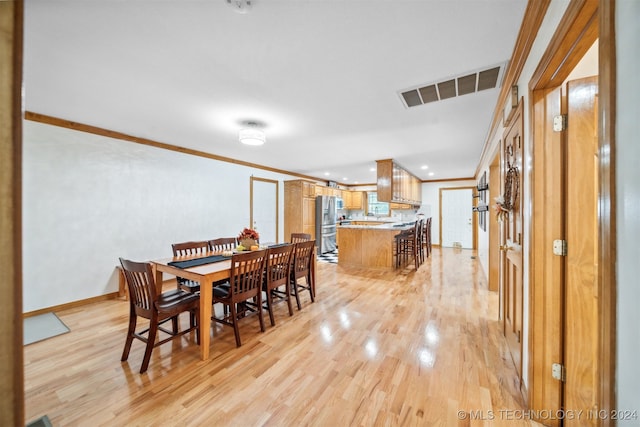 dining room with light hardwood / wood-style floors and ornamental molding