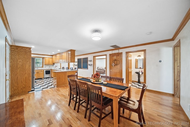 dining room with light wood-type flooring and crown molding