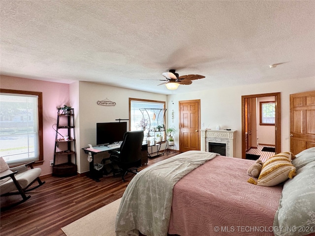 bedroom with multiple windows, dark hardwood / wood-style floors, ceiling fan, and a textured ceiling