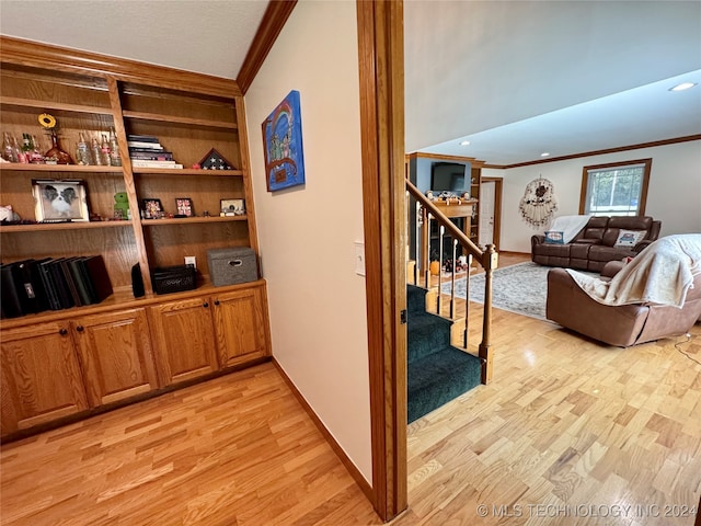 hall with ornamental molding and light hardwood / wood-style flooring