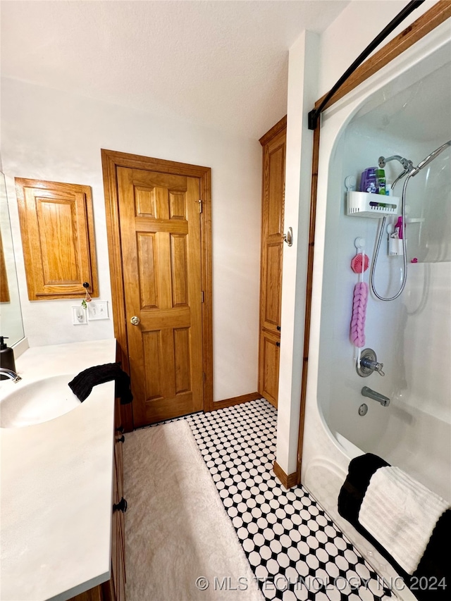 bathroom featuring shower / tub combination, vanity, and a textured ceiling