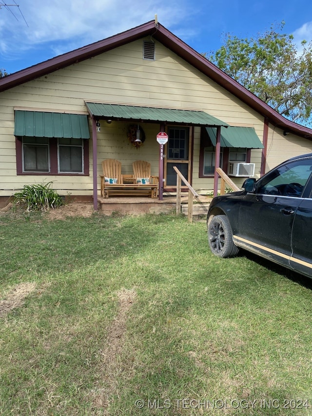 view of front of home with cooling unit, a porch, and a front lawn