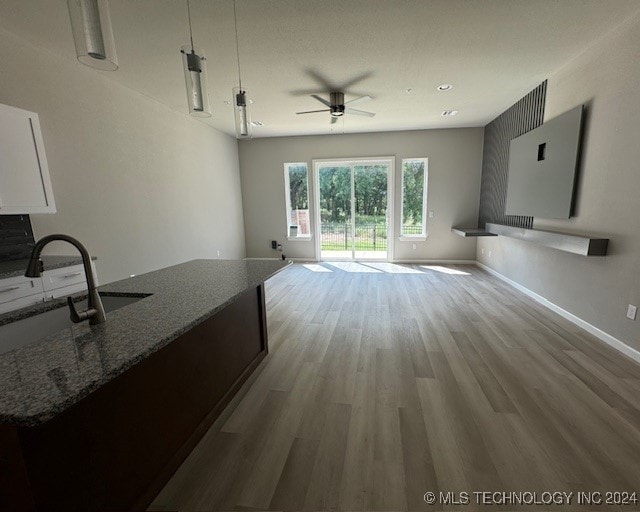 unfurnished living room featuring ceiling fan, light wood-type flooring, and sink