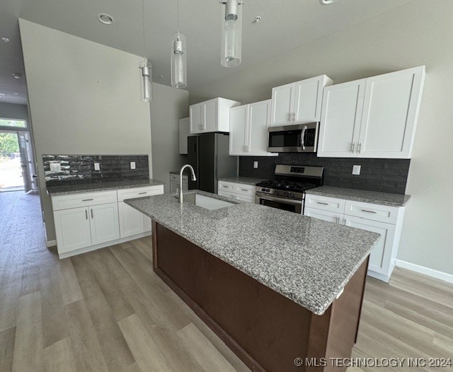 kitchen with appliances with stainless steel finishes, hanging light fixtures, tasteful backsplash, and sink