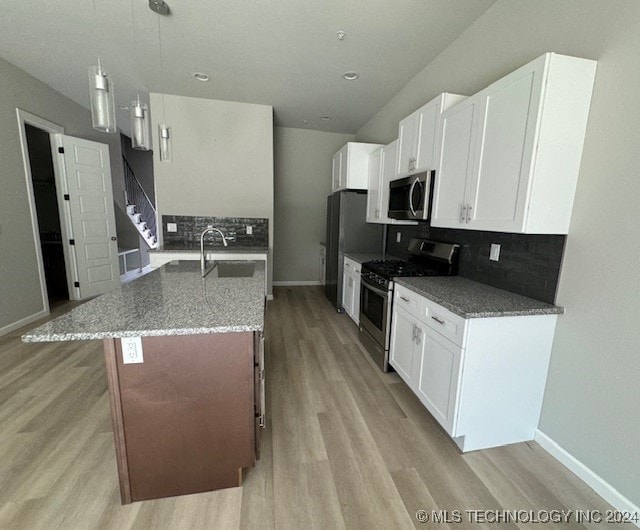 kitchen featuring pendant lighting, stone countertops, backsplash, white cabinetry, and stainless steel appliances