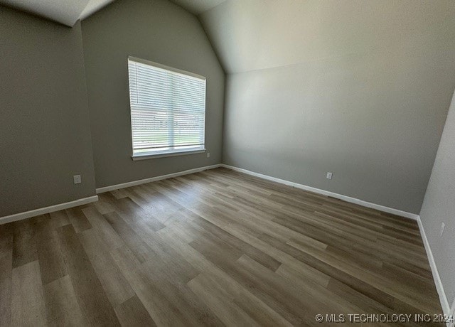 spare room featuring hardwood / wood-style flooring and lofted ceiling