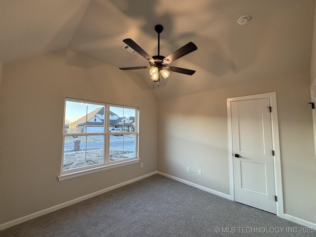 unfurnished room featuring dark carpet, vaulted ceiling, baseboards, and a ceiling fan