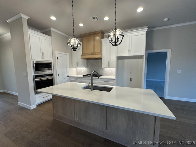 kitchen featuring an island with sink, appliances with stainless steel finishes, sink, and white cabinets