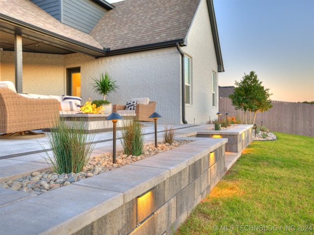 property exterior at dusk featuring a patio and a yard