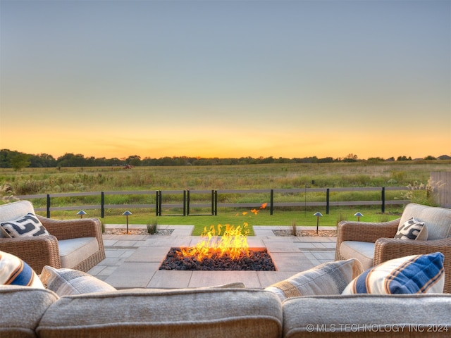 patio terrace at dusk featuring a fire pit and a rural view