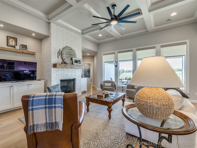 living room with light wood-type flooring, beamed ceiling, a wealth of natural light, and coffered ceiling