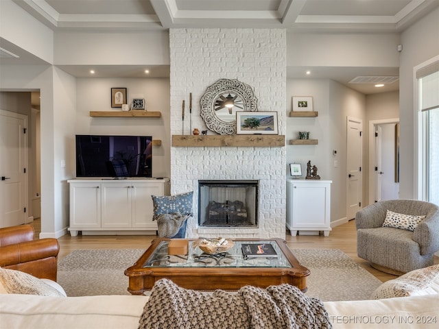 living room with beamed ceiling, light hardwood / wood-style flooring, and a brick fireplace