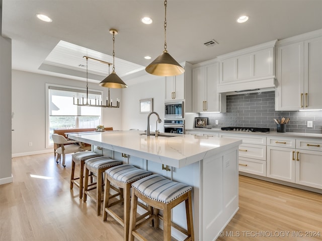 kitchen with white cabinets, a kitchen island with sink, and stainless steel appliances