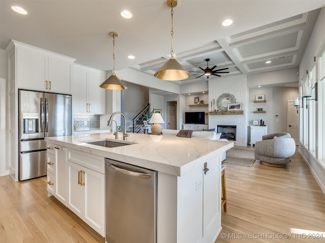 kitchen with white cabinets, appliances with stainless steel finishes, a kitchen island with sink, and sink