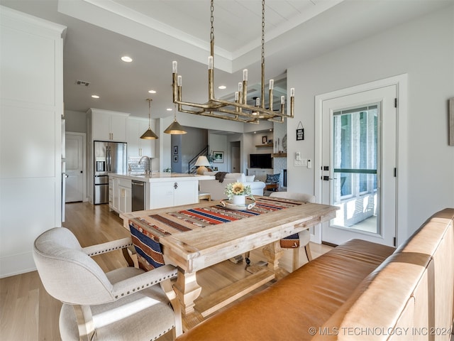 dining area with light hardwood / wood-style flooring, sink, and a tray ceiling