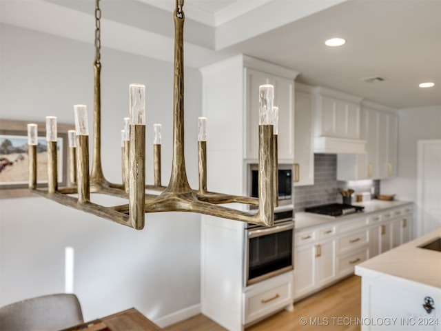 kitchen with black gas stovetop, decorative backsplash, white cabinetry, and light hardwood / wood-style flooring