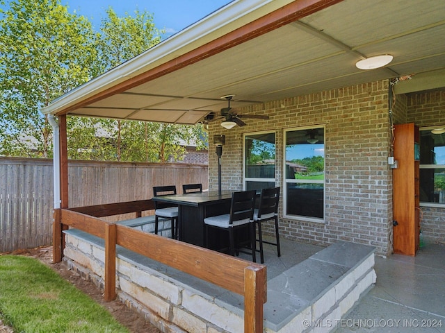 view of patio / terrace with outdoor dry bar, a ceiling fan, and fence