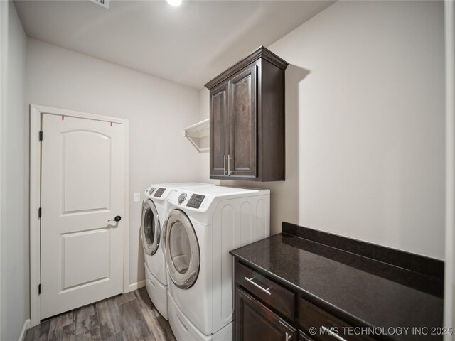 washroom featuring dark wood-type flooring, cabinet space, and washing machine and clothes dryer