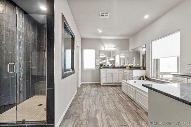 full bathroom featuring vanity, baseboards, visible vents, a shower stall, and a bath