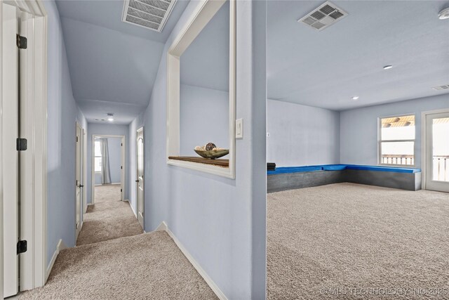 hall featuring visible vents, carpet floors, and baseboards