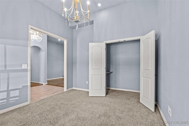 unfurnished bedroom with arched walkways, carpet flooring, and baseboards