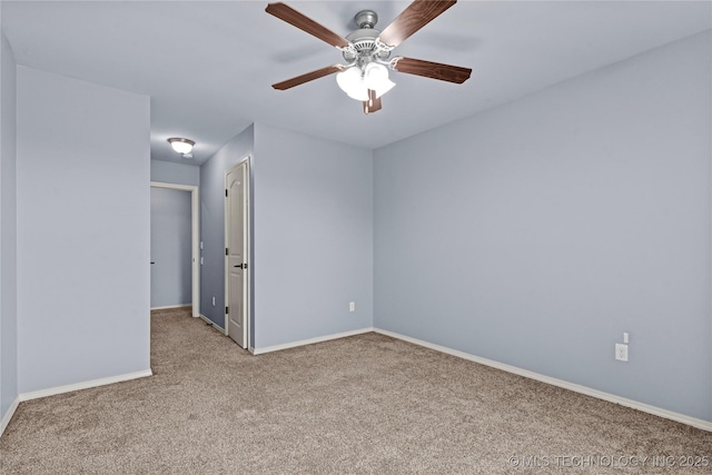 carpeted spare room with a ceiling fan and baseboards