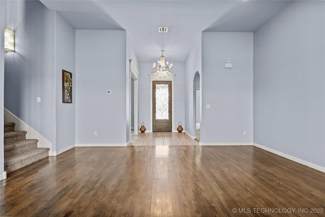 foyer entrance with stairway, wood finished floors, visible vents, baseboards, and a chandelier