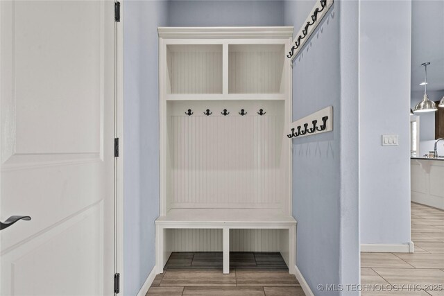 mudroom featuring wood finish floors, a barn door, and baseboards