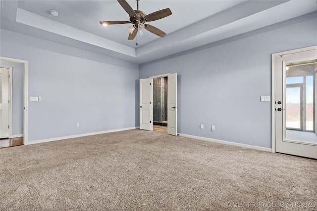 carpeted spare room with ceiling fan, baseboards, and a tray ceiling