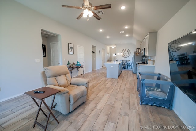 living room featuring light wood-type flooring, ceiling fan, lofted ceiling, and sink