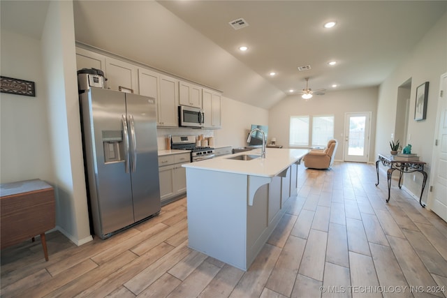 kitchen featuring appliances with stainless steel finishes, sink, vaulted ceiling, ceiling fan, and a center island with sink