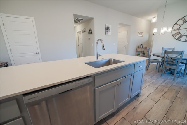 kitchen with stainless steel dishwasher, sink, hanging light fixtures, gray cabinetry, and a chandelier