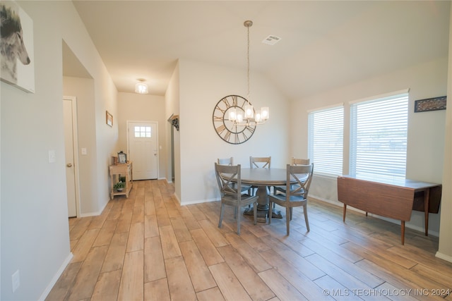 dining area with lofted ceiling, light wood-type flooring, and an inviting chandelier