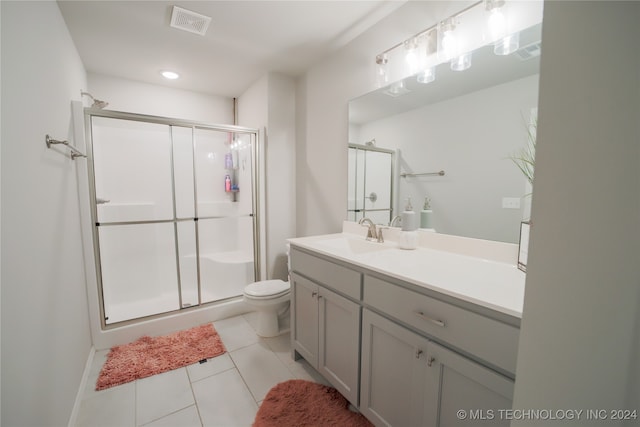 bathroom with toilet, vanity, tile patterned flooring, and a shower with door