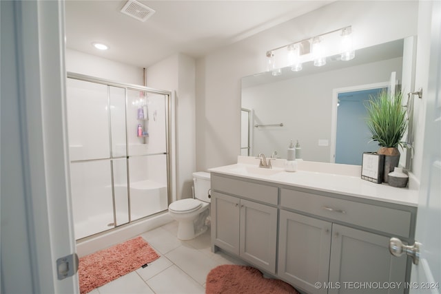 bathroom featuring toilet, tile patterned flooring, a shower with shower door, and vanity