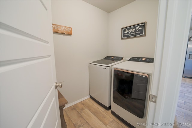 clothes washing area featuring light hardwood / wood-style floors and washer and clothes dryer