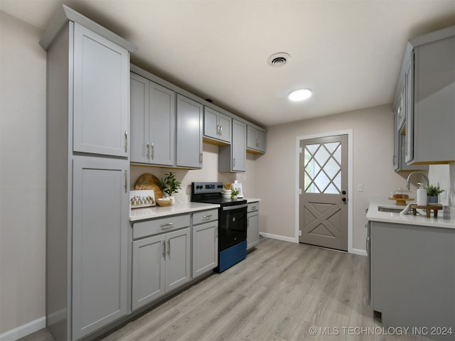 kitchen featuring gray cabinets, sink, light hardwood / wood-style floors, and black / electric stove