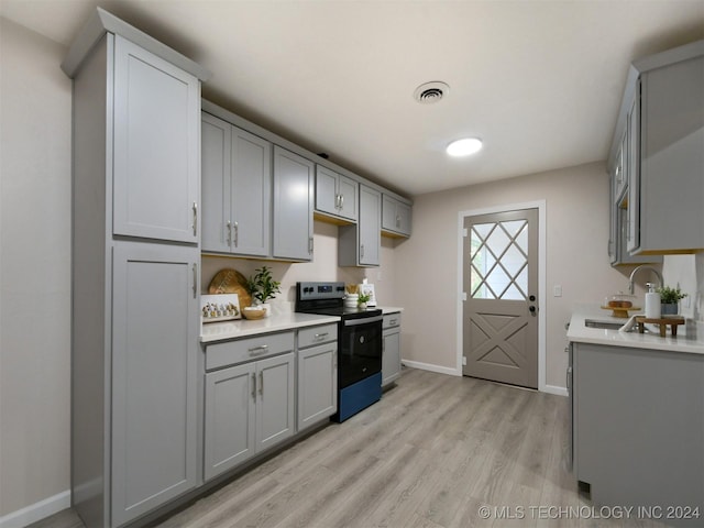 509 G St SW, Ardmore, OK 73401 - kitchen with light countertops, gray cabinets, light wood-style floors, and stainless steel electric range