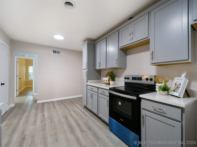 kitchen featuring stainless steel electric range oven, light hardwood / wood-style floors, and gray cabinetry