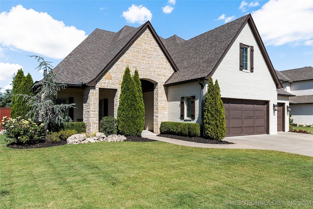 french country style house featuring a garage and a front lawn