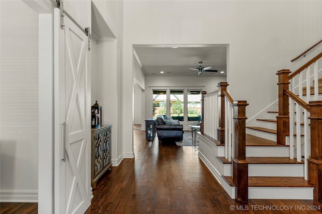 foyer entrance featuring dark wood-type flooring, a barn door, and ceiling fan