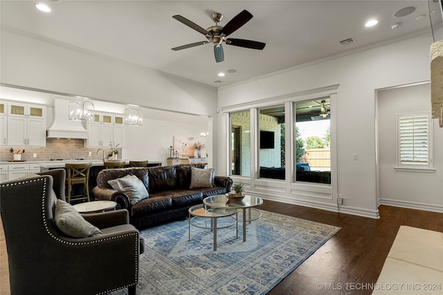 living room with dark wood-type flooring, crown molding, and ceiling fan