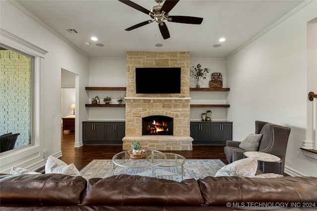 living room with ceiling fan, a stone fireplace, ornamental molding, and dark hardwood / wood-style floors